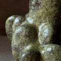 Close-up of a sculptural ceramic vase with organic, rounded forms and a glossy finish in olive green and brown tones.