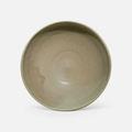 A single ceramic bowl with a wide rim, featuring a smooth, matte sage green glaze with subtle earthy brown undertones, photographed against a clean white background.