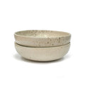 Two beige speckled ceramic bowls stacked on a white background