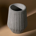 Textured gray cylindrical vase on a brown background