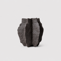 A dark charcoal gray, textured stone-like vase with a ribbed, organic shape, photographed against a clean, light gray background.