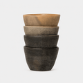 Stack of four ceramic bowls in varying shades of brown on a white background