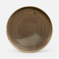 A round ceramic plate with a rustic, brown glaze and a contrasting light beige rim, shown against a plain light gray background.