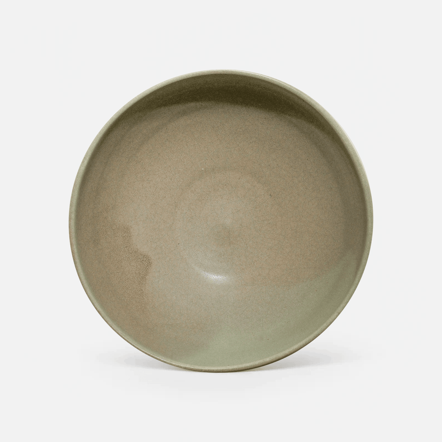 A single ceramic bowl with a wide rim, featuring a smooth, matte sage green glaze with subtle earthy brown undertones, photographed against a clean white background.