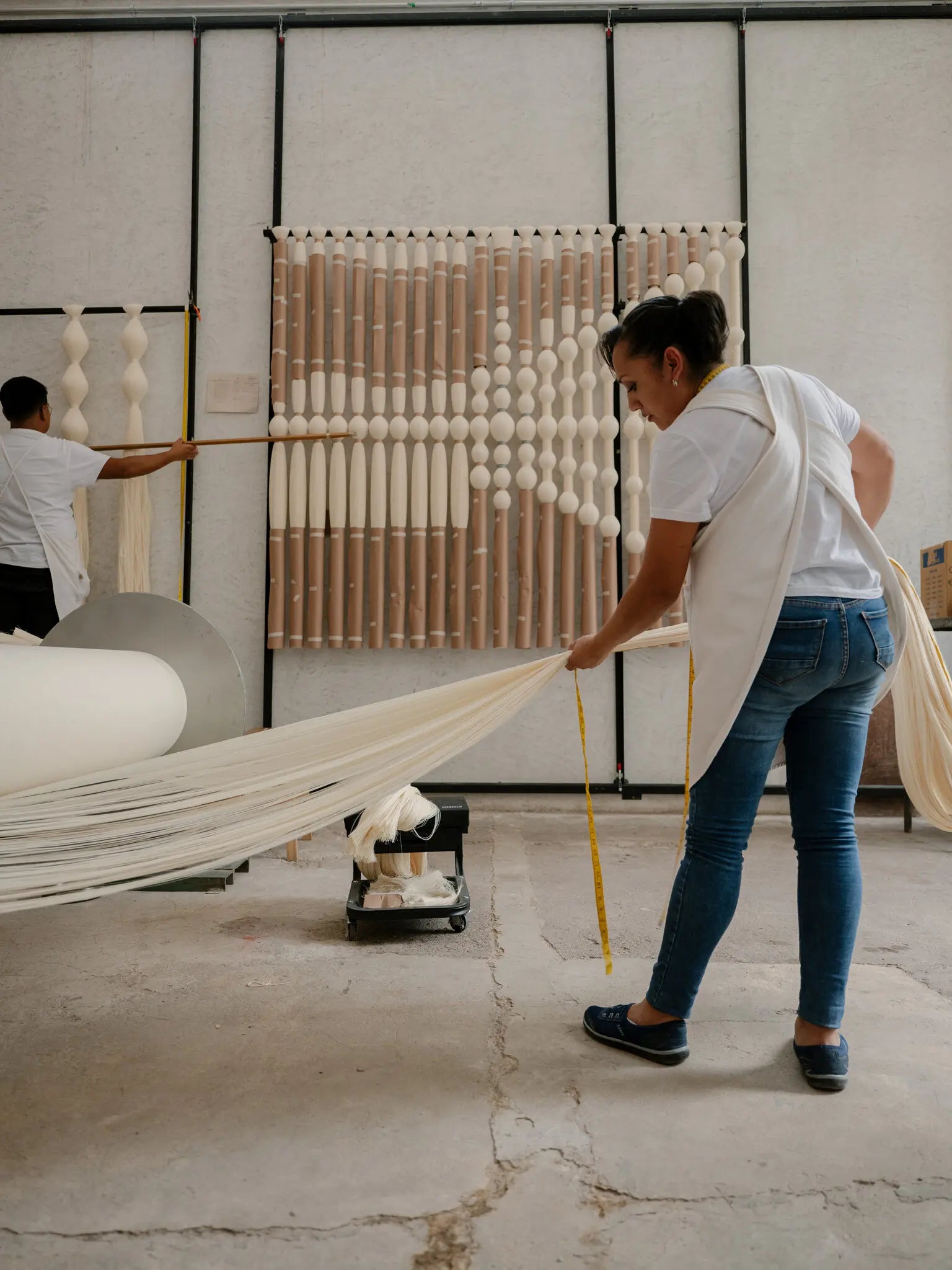Two people working with fabric and a measuring tape in an indoor setting at caralarga mexico - textile design and production studio