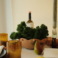 Dining table setting with pears, candles, and a bottle of wine.