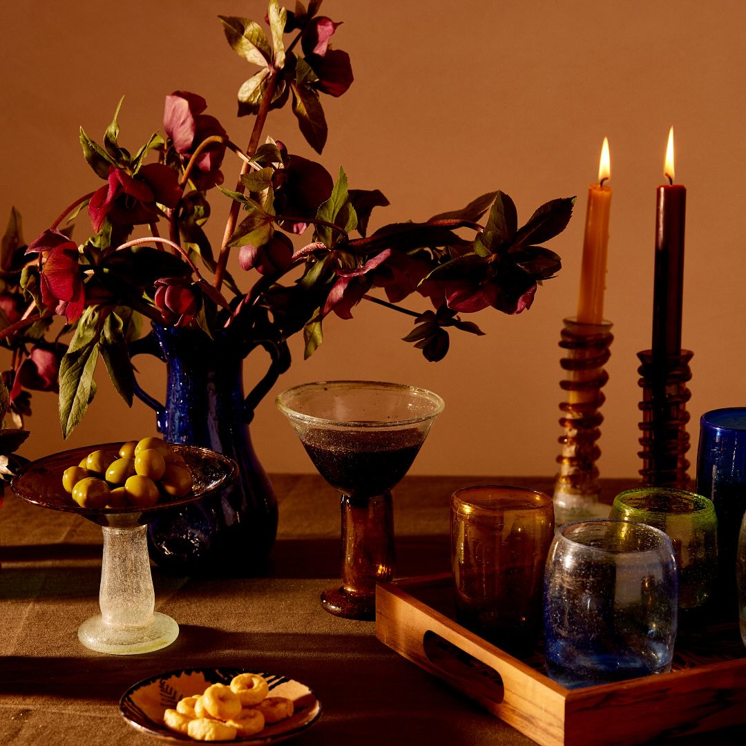 Decorative table setting with flowers, candles, and glasses against a warm brown background