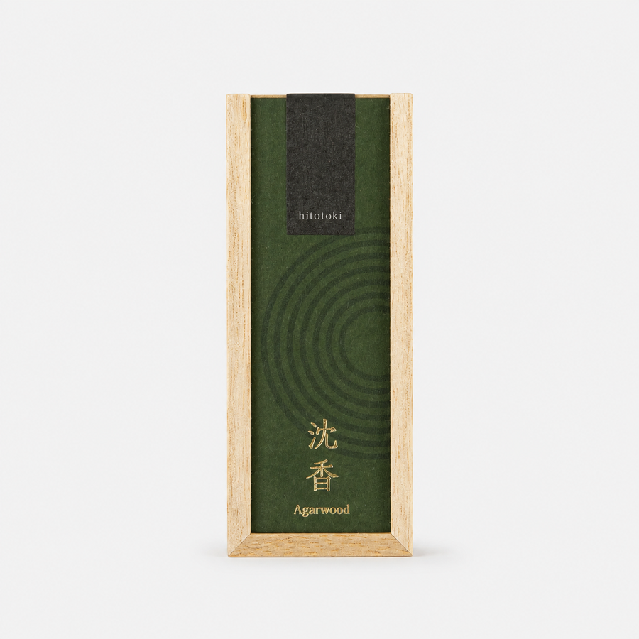 A rectangular wooden incense box with a dark green lid with the words Hitotoki Agarwood printed on it, shown on a clean white background. 