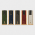 Five rectangular incense boxes in light wood frames with different colored inner labels are lined up on a light gray background. The labels show gold Chinese characters and English scent names including Agarwood, Ambergris, Sandalwood, Magnolia, and Musk.