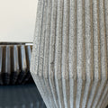 Textured vase on a reflective surface with a blurred background