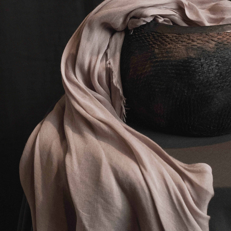 A scarf is stuffed inside of a clay vase.
