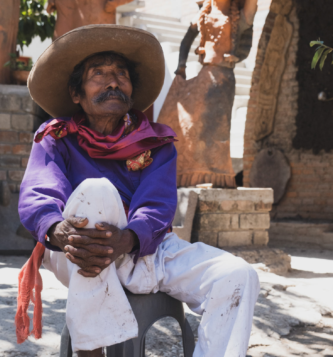 Jose Garcia sitting outdoors wearing a wide-brimmed hat and purple shirt, holding a white object. Obakki Film featured