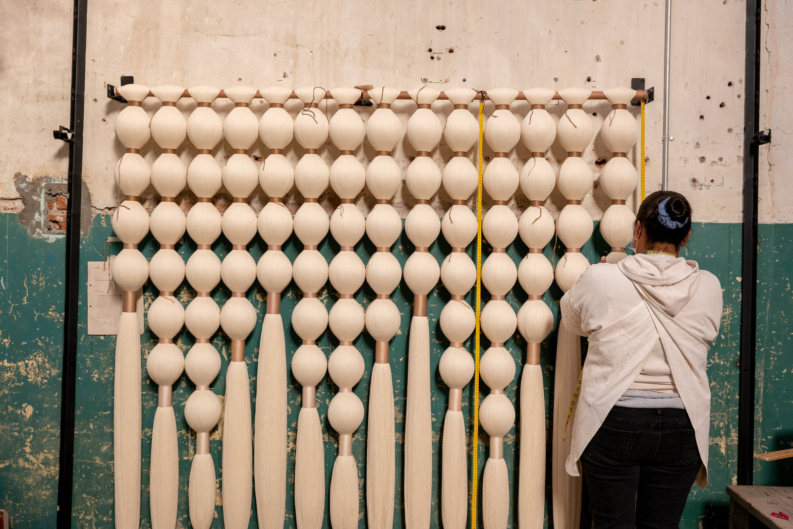 A woman measures a wall hanging in the Caralarga workshop.