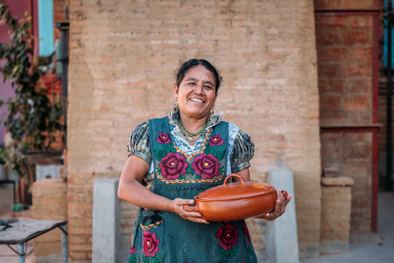 Macrina smiling while holding a clay casserole dish she made. 