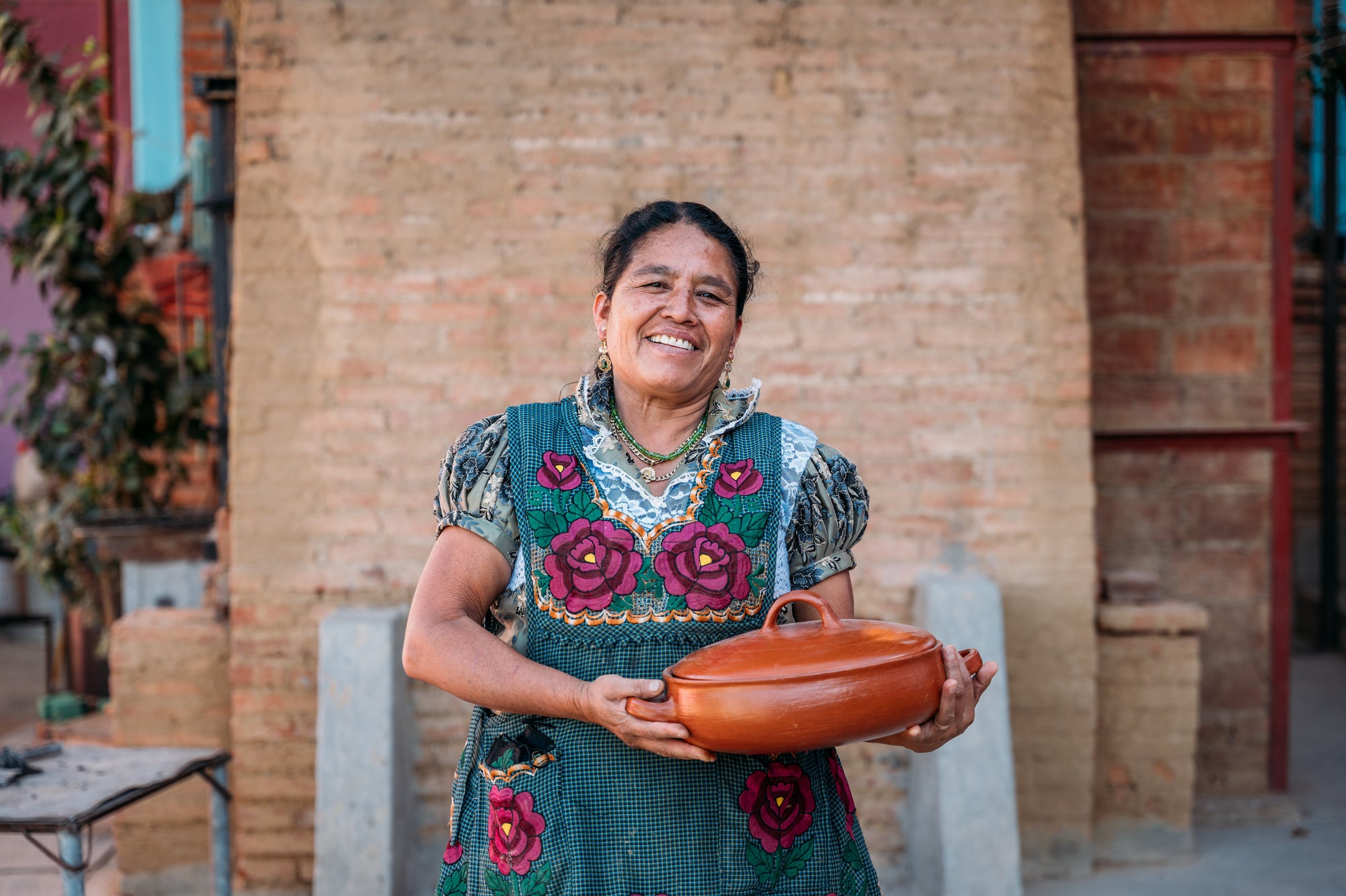 Macrina smiling while holding a clay casserole dish she made. 
