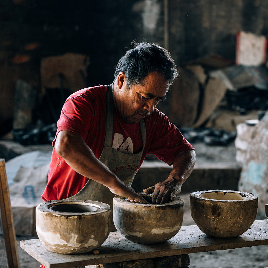 Man working with clay pots in a workshop setting
