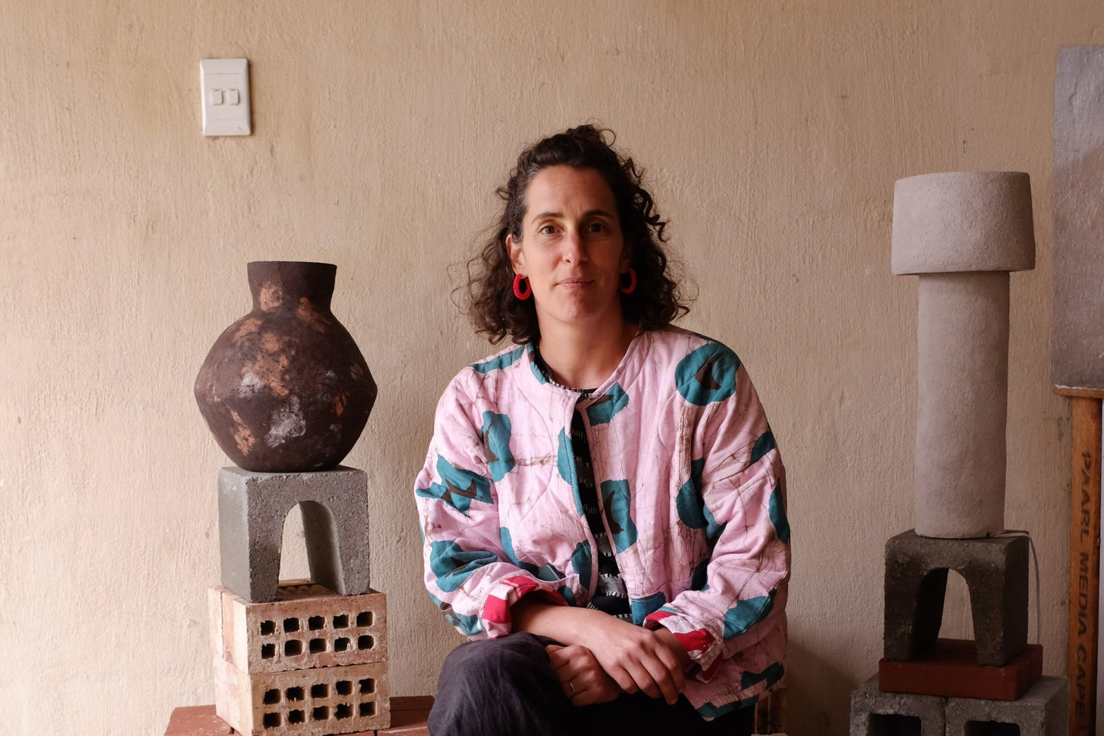 Person sitting among ceramic sculptures in a home setting