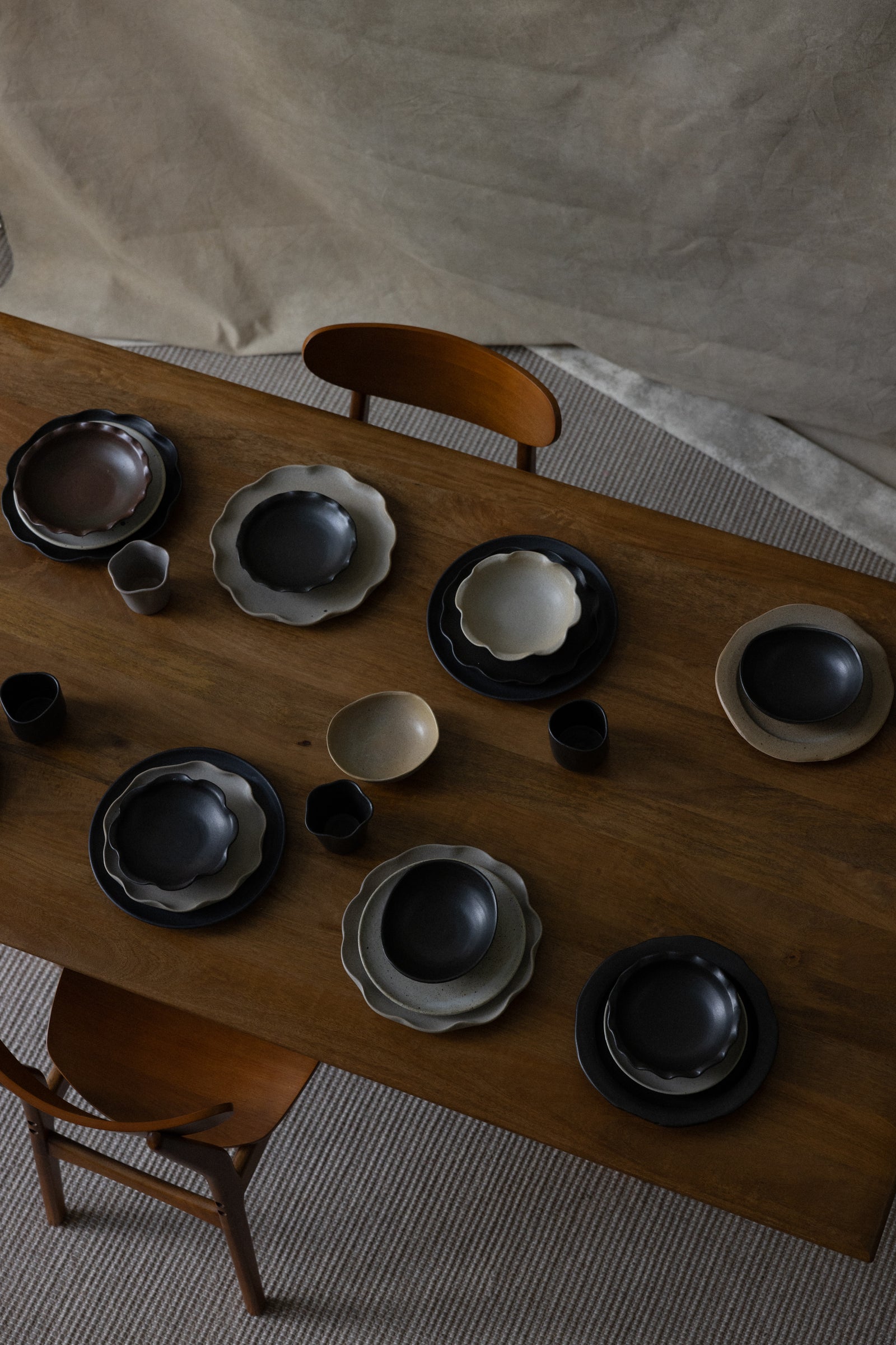 Ceramic bowls and plates on a wooden table with chairs in a room.