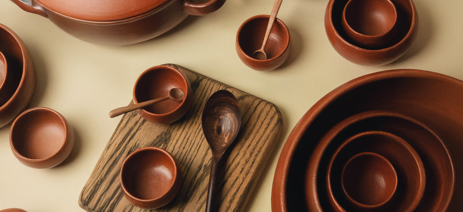 A variety of red clay bowls, and wooden spoons.