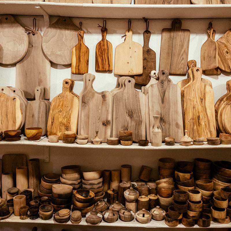Display of various wooden kitchen items including cutting boards and bowls on shelves.