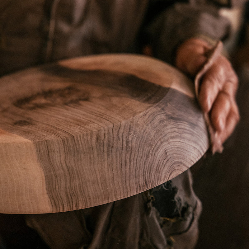 Person holding a wooden cutting board with visible grain and texture
