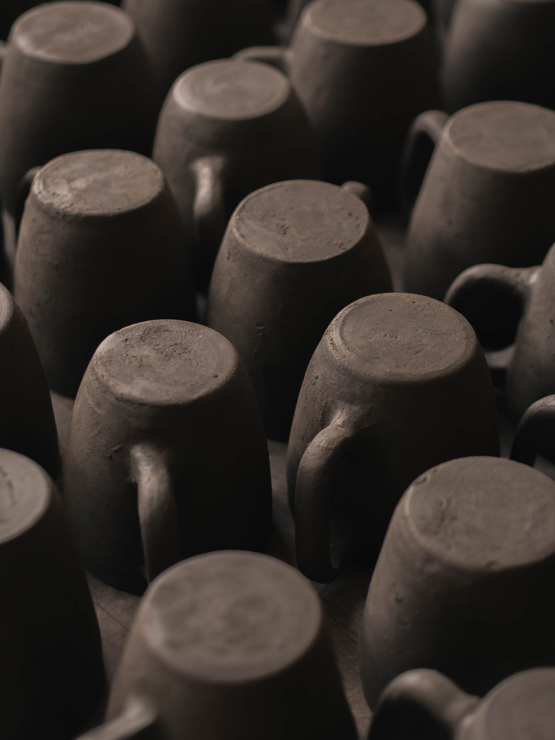 Close-up of multiple black clay cup with in a dark setting