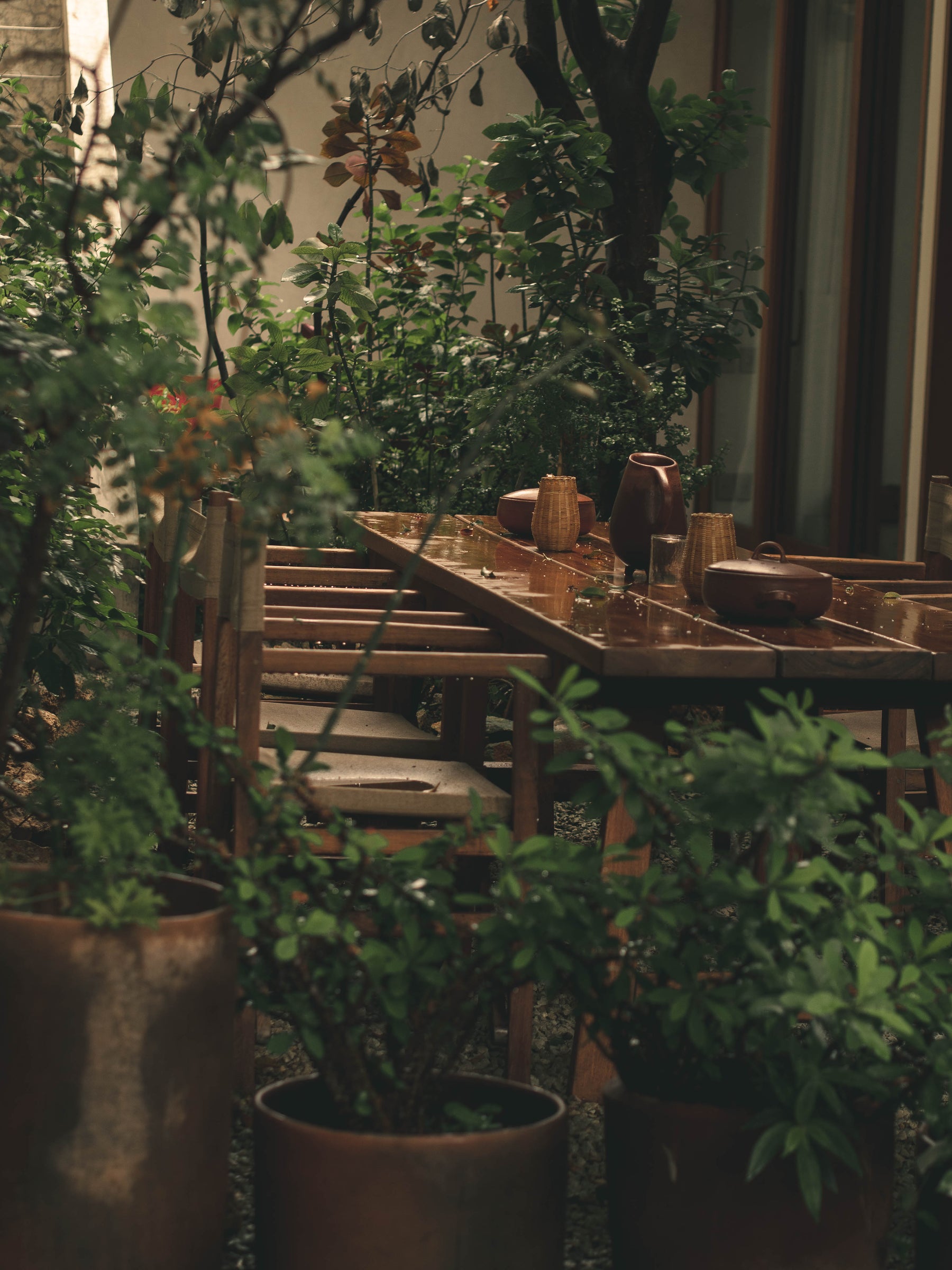 outdoor setting with wooden tables and chairs with red clay pottery tableware in oaxaca under rain