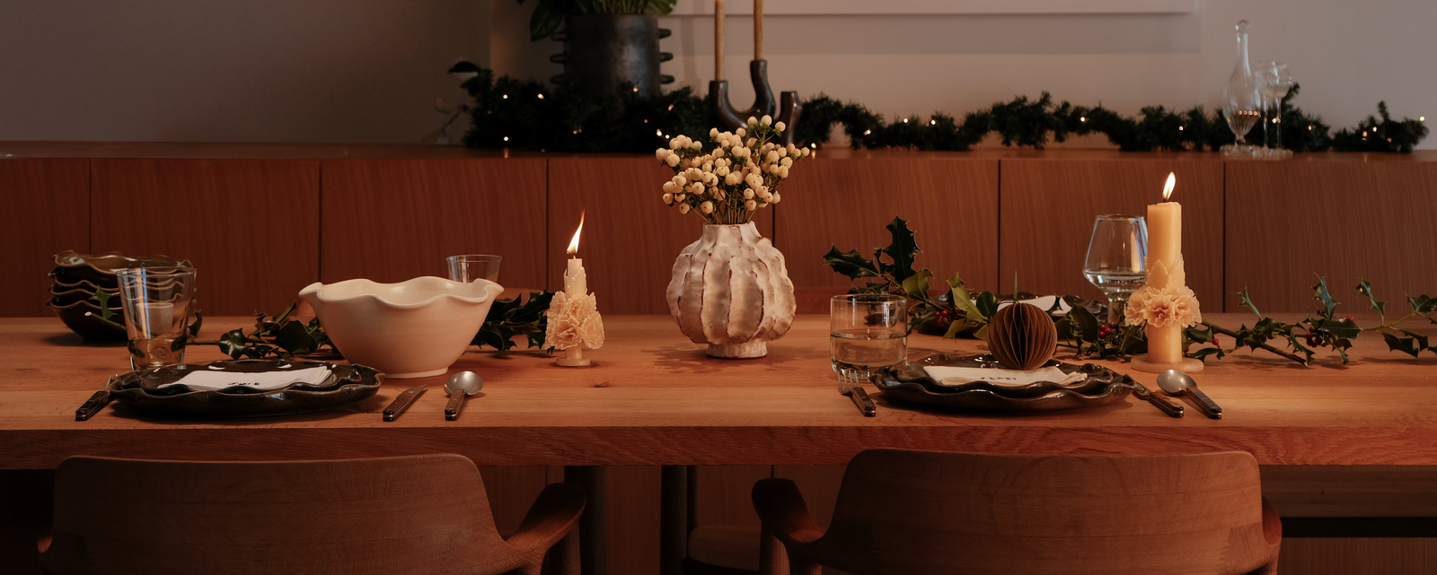 Dining table set for a meal with candles, glasses, and cutlery in a warm setting.