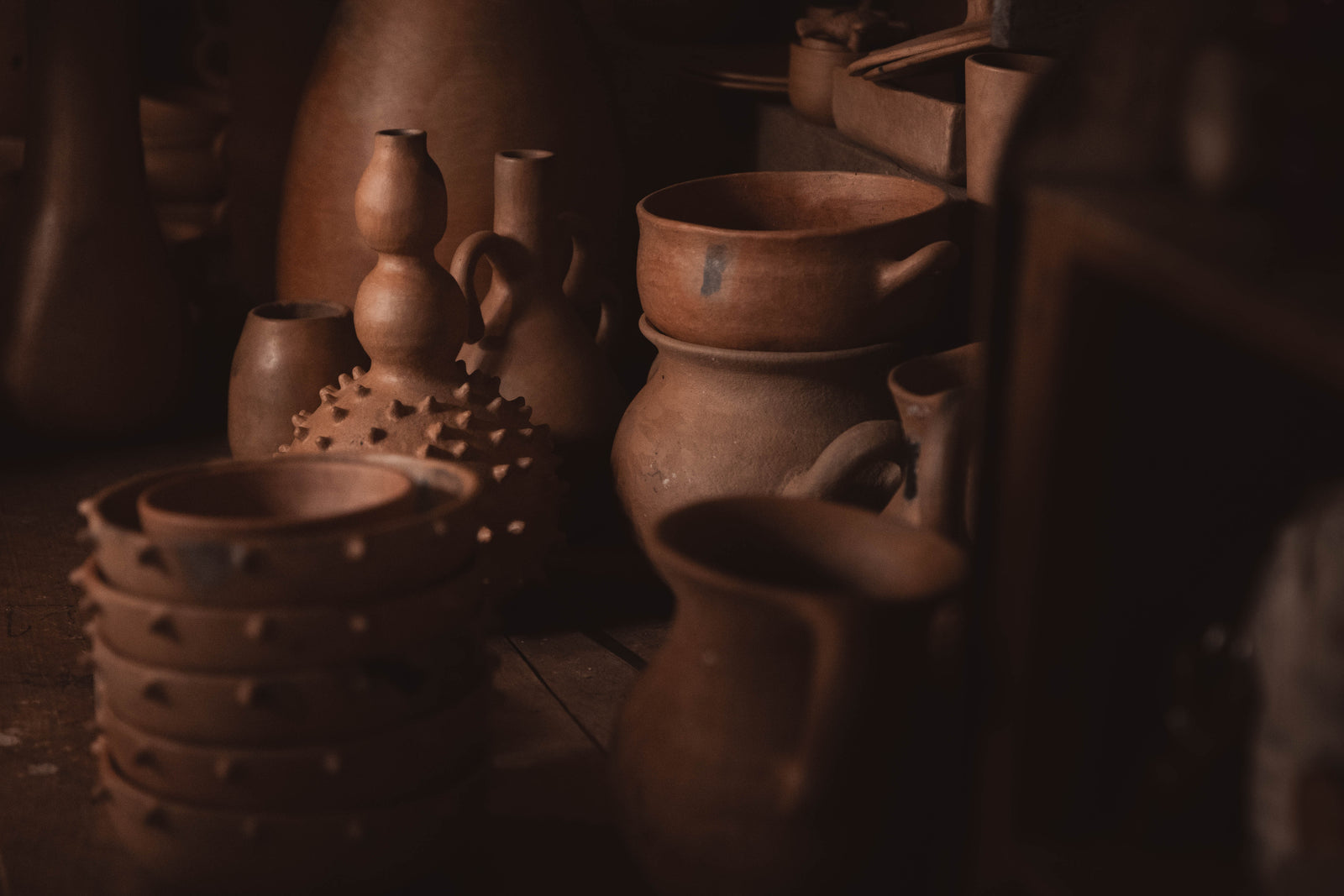 Collection of terracotta pots and bowls on a wooden surface with a warm brown color tone.