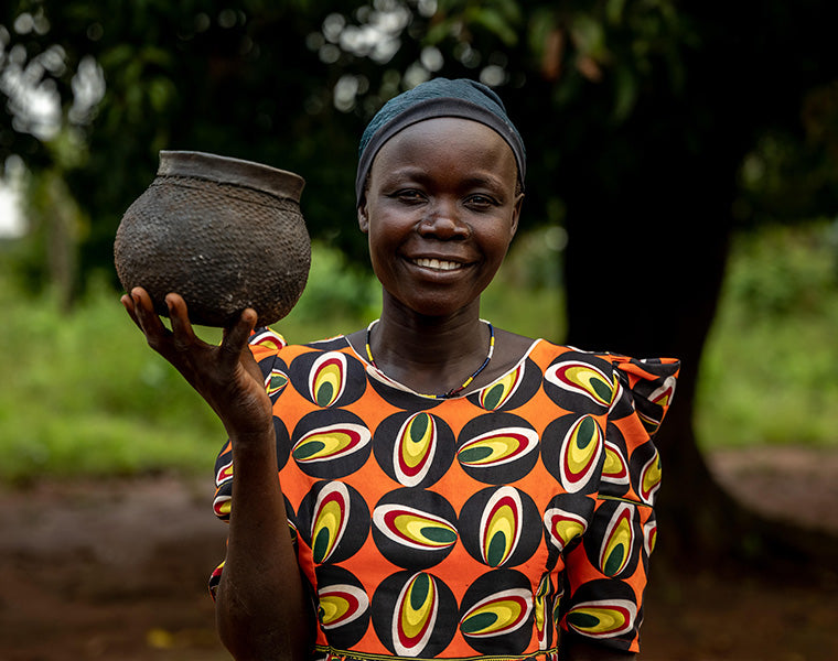 A woman from Akiliba holding a clay pot she made.