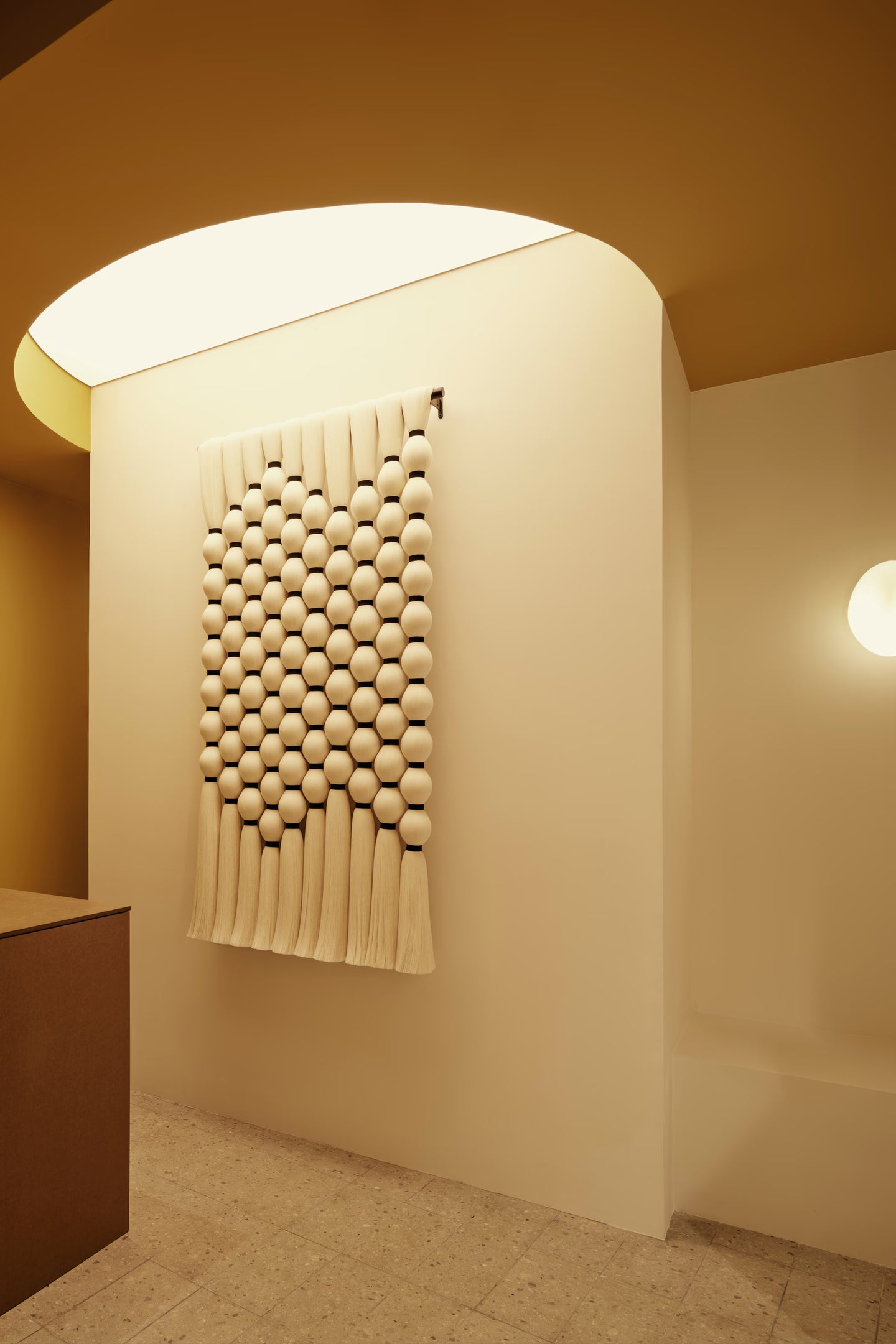 Handcrafted Caralarga wall hanging made from sculptural textile elements, displayed in a minimalist retail store.