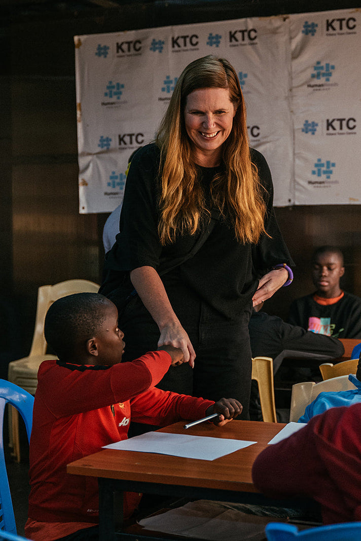 Woman interacting with children at a table in front of KTC banners
