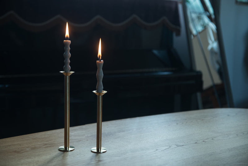 Two candle holders host two sumac candles to pair. They sit on a wooden table.