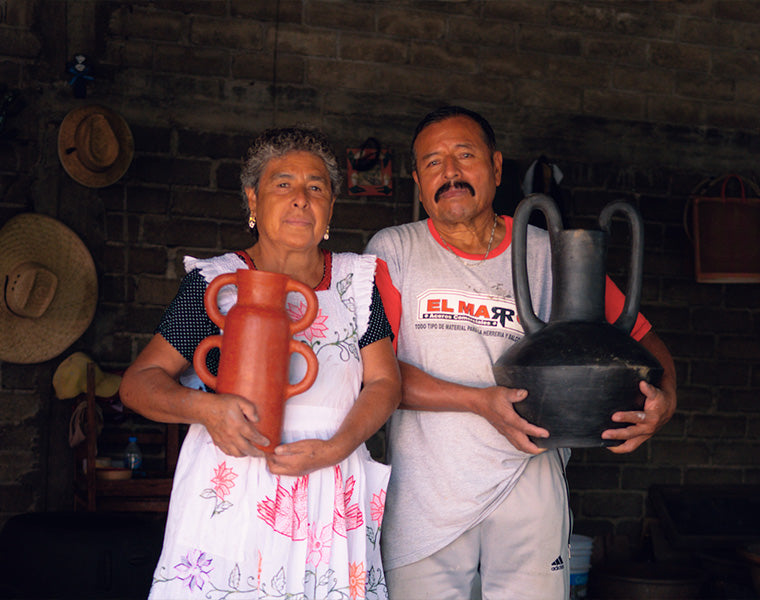 A man and a woman hold two clay vases.