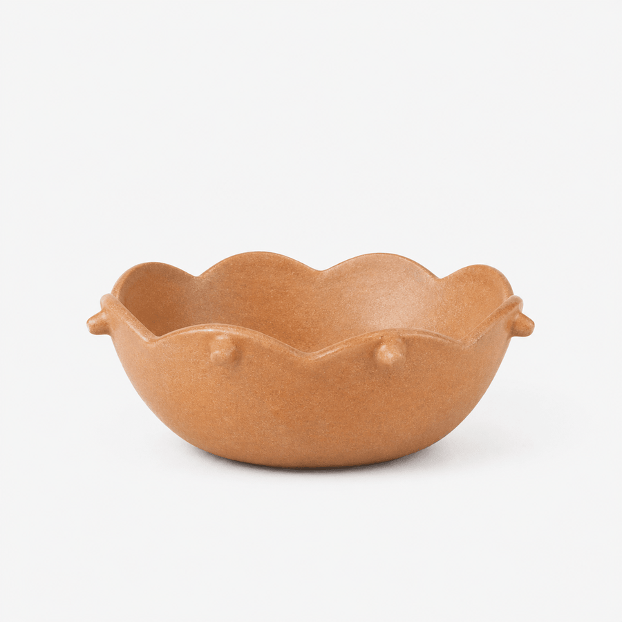 Brown ceramic bowl with scalloped edge on a white background
